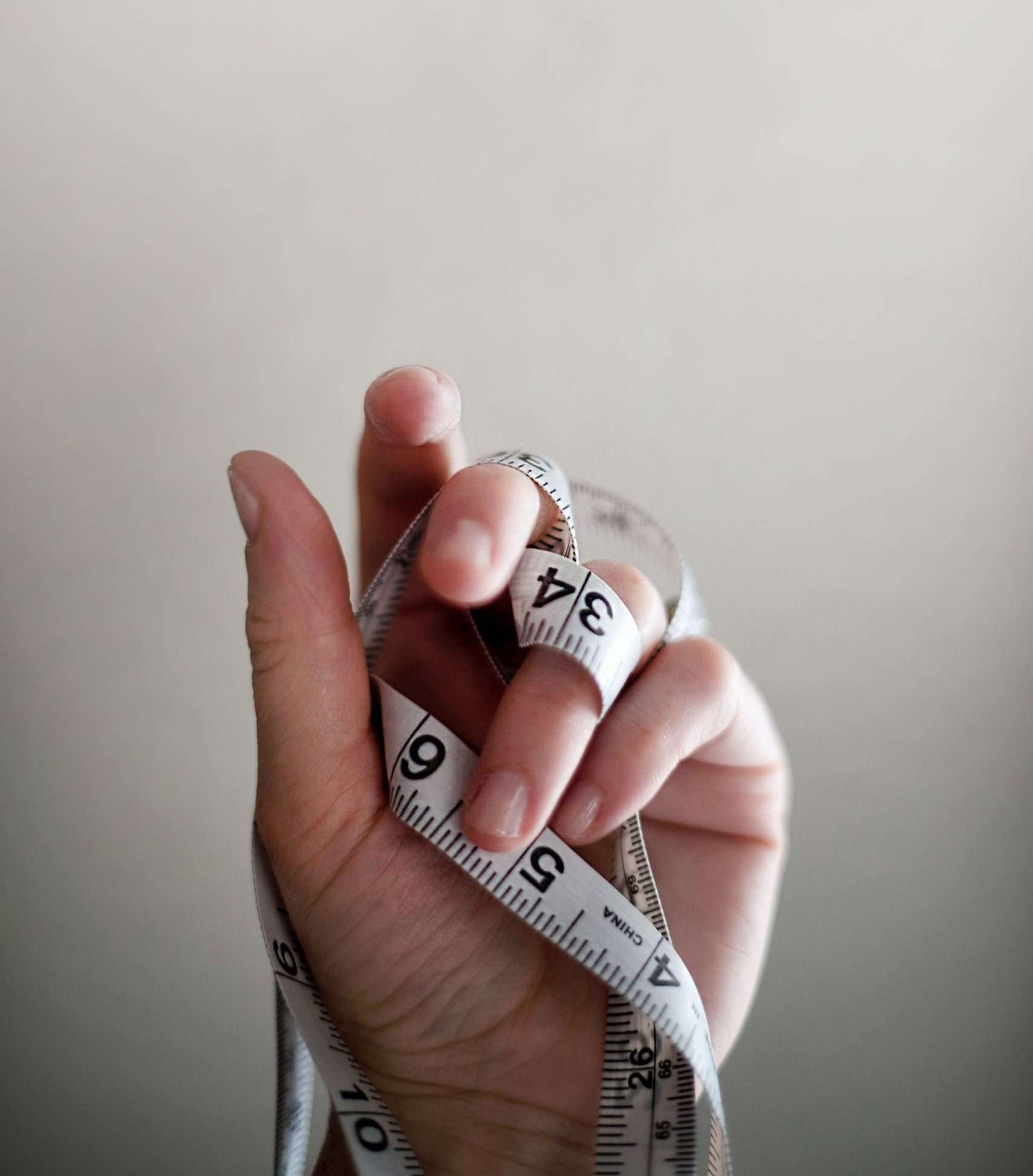 Hand holding measuring tape used to measure body weight