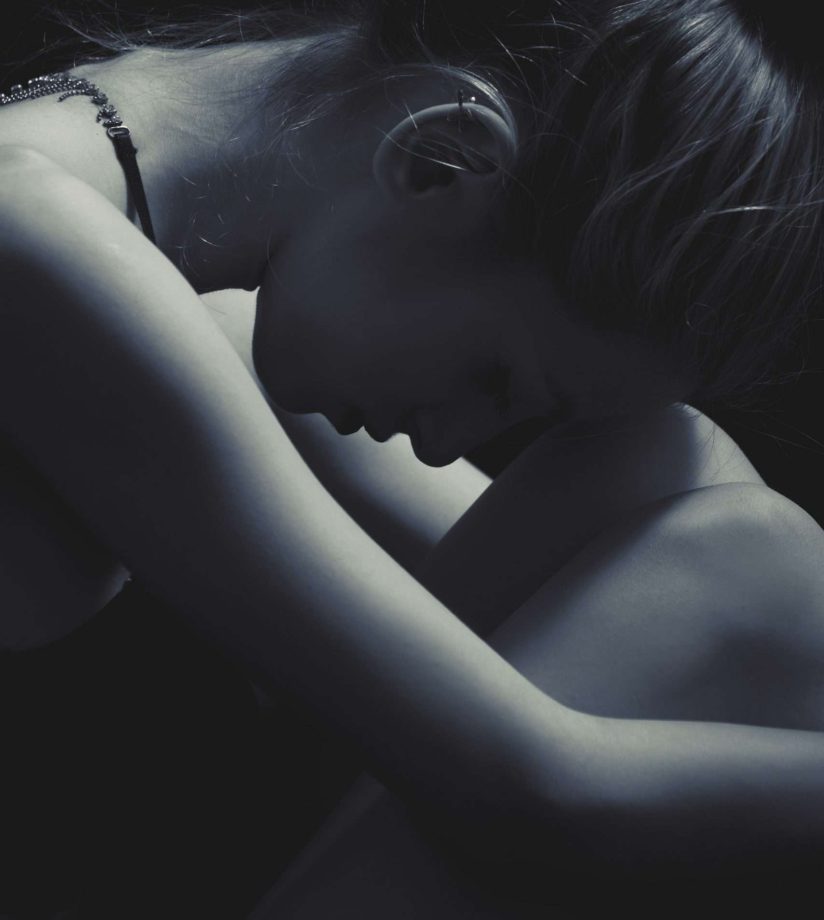 Black and white image of a woman with an eating disorder, huddled over