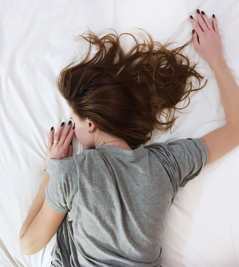 A tired woman with insomnia lying on white sheets.jpg